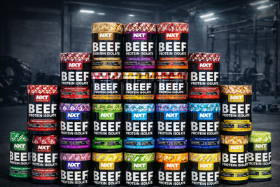 Stack of various flavors of NXT Beef Protein Isolate containers in a gym setting.