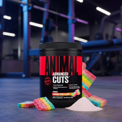 Black container of Animal Cuts supplement with rainbow candy on a gym floor.