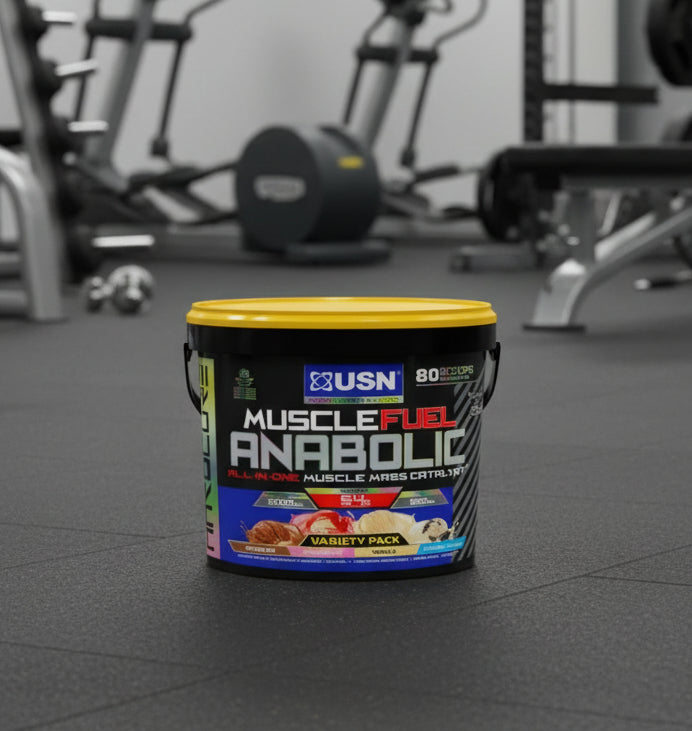 USN Muscle Fuel Anabolic supplement container on a gym floor with exercise equipment in the background