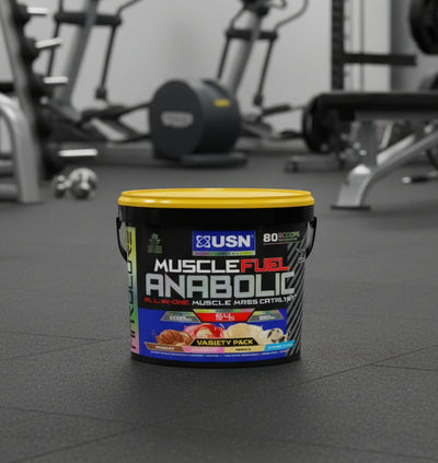 USN Muscle Fuel Anabolic supplement container on a gym floor with exercise equipment in the background